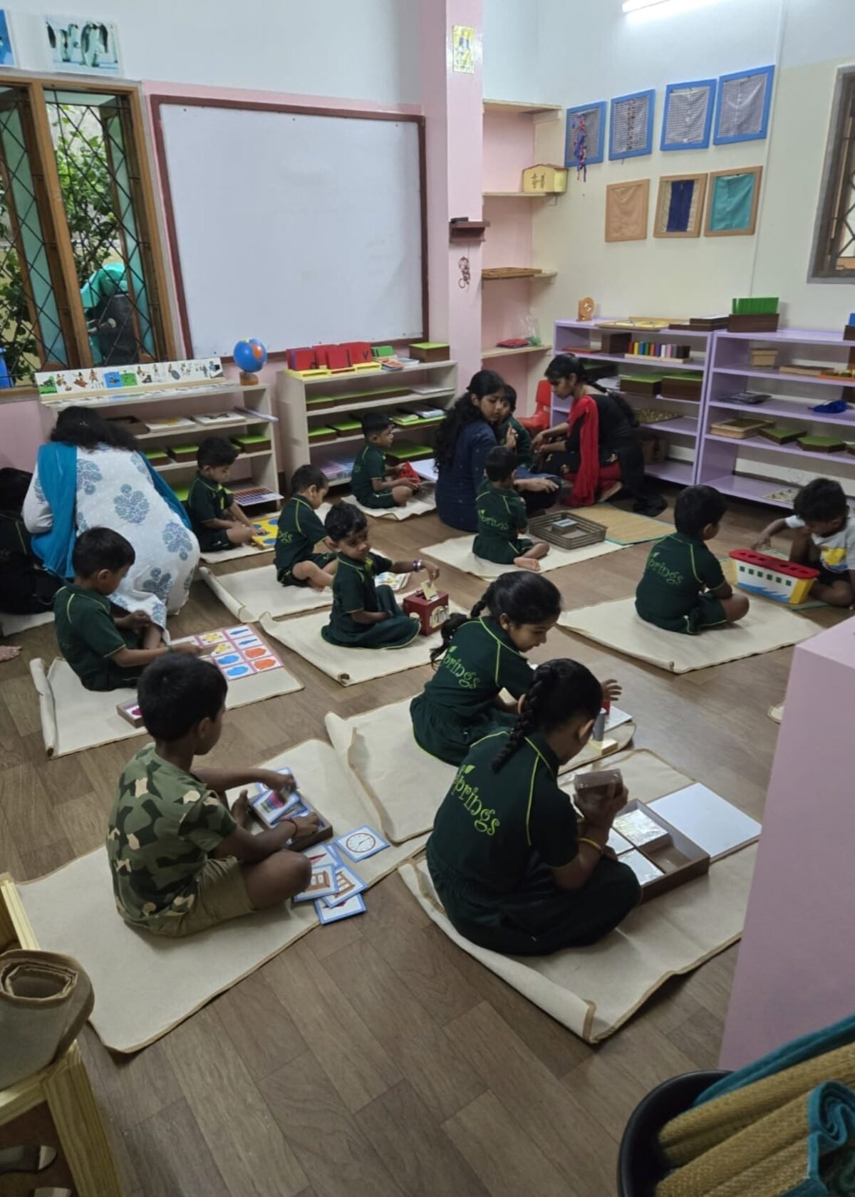 Teacher guiding a small group Montessori floor activity